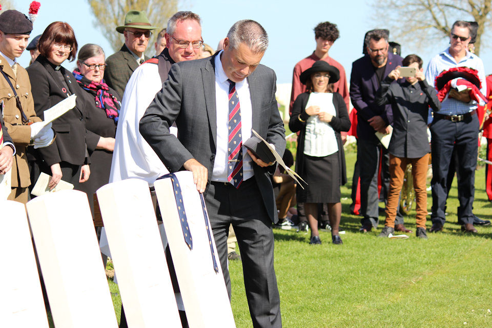 The current headmaster of Captain Walker’s school lays a school tie on his headstone, Crown Copyright, All rights reserved