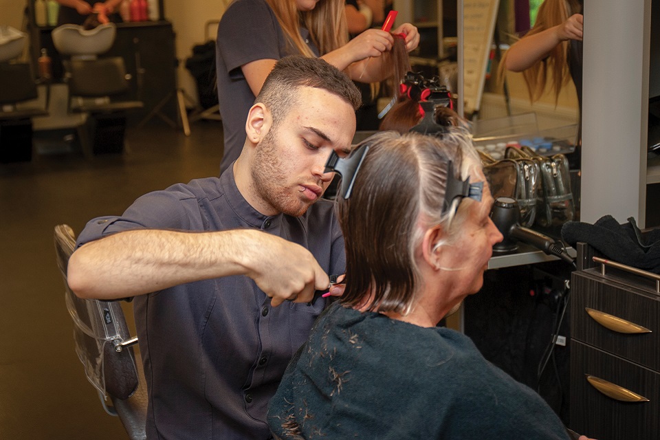Male student cutting a woman's hair