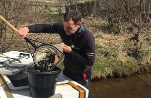 Image shows Richard Bond releasing trout into the River Tyne catchment