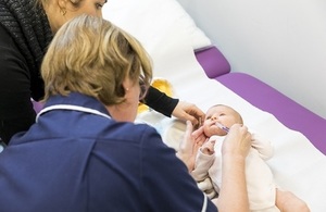 Close-up of a nurse giving a baby medicine through a tube.