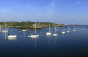 Boats moored off an island shore.