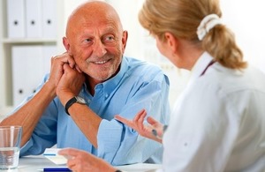 A doctor talks with a senior male patient via Alexander Raths at Shutterstock