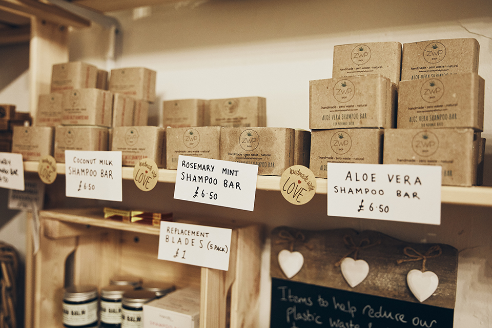 A variety of soaps and shampoo bars on a wooden shelf in the Eco Larder shop.