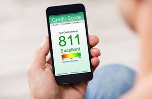 A photograph of a person checking their credit score on a mobile phone.