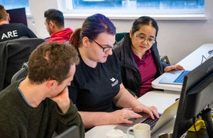 Three people working on a laptop