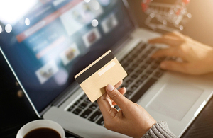 Person holding their credit card in front of a laptop.