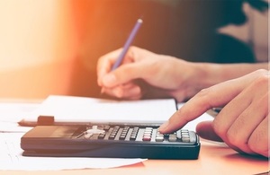 photograph of someone doing calculations using a calculator and pen and paper