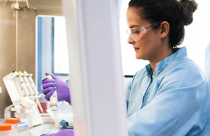 An image of a woman in lab wear testing a sample.