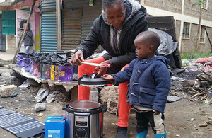 A child and parent use an electric alternative to biomass fuel cooking