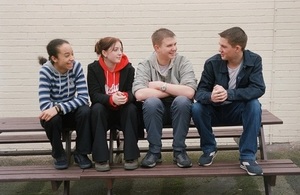 Four teenagers sitting on a bench talking together