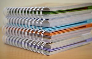 Four coloured notebooks stacked on a desk