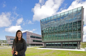 Image of: Sara holding award in front of SLC Wales Building