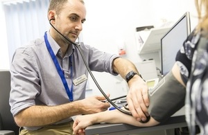 A doctor using a stethoscope on a patient's arm.