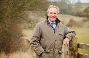 A picture of Sir William Worsley leaning on a fence in a field.