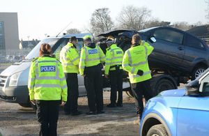 Police officers and Environment Agency officers examining a scrap car loaded on the back of a truck
