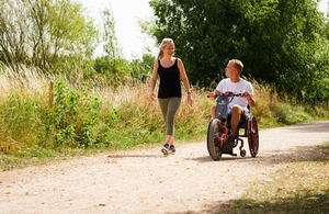 A woman walks besides a man in a wheelchair.