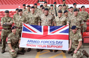 Members of the Armed Forces in uniform with the Armed Forces Day flag.