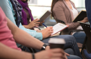 Close up of people sitting down at a meeting.