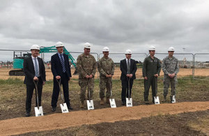 Senior leaders from various organisations , some in military uniform, standing in front on the construction ground for the new F-35 aircraft.