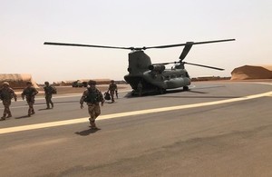 Soldiers in desert camo gear exit a chinnock.