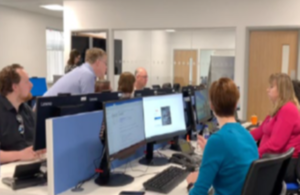 Photograph of people sitting around desks