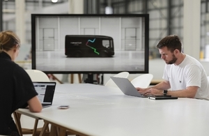 Vehicle on screen and men looking at laptop