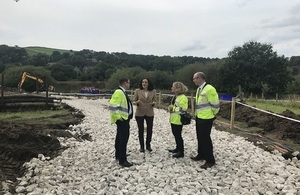 A picture of Theresa Villiers and Emma Howard Boyd with two officials in front of a dam with a crane in the background.