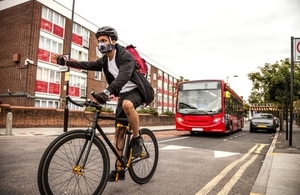cyclist wearing a pollution filtering mask riding in front of a bus