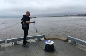 An Environment Agency officer taking a bathing water sampling off Bridlington harbour wall
