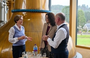 A picture of Environment Secretary with a man and a woman tasting scotch in front of a window.