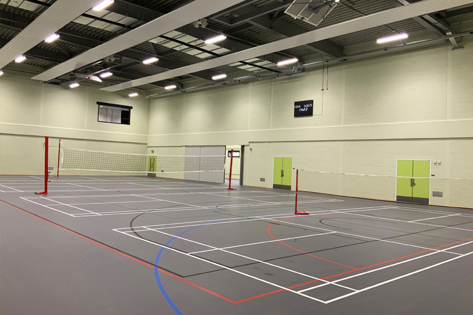 Photo shows the interior of the new sports centre at Worthy Down. Tennis courts are seen, and markings for basketball training.