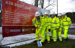 Men and women wearing yellow protective clothing and hard hats standing next to sign for the A38 Selly Oak cycle route