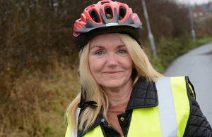 Woman in high visibility jacket and cycle helmet standing with bicycle