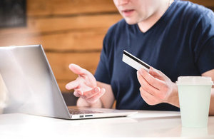Person using laptop holding a credit card