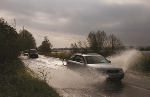 Car driving through surface water on country road