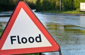Image of a flood sign against a flooded backdrop.