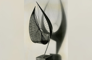 A curved bronze sculpture on a wooden base