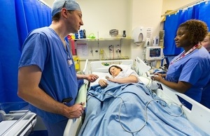 Medical staff talking to patient in bed.