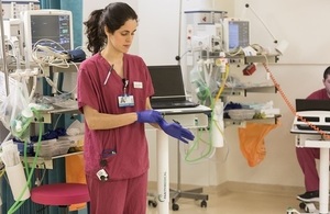 A theatre practitioner putting on surgical gloves