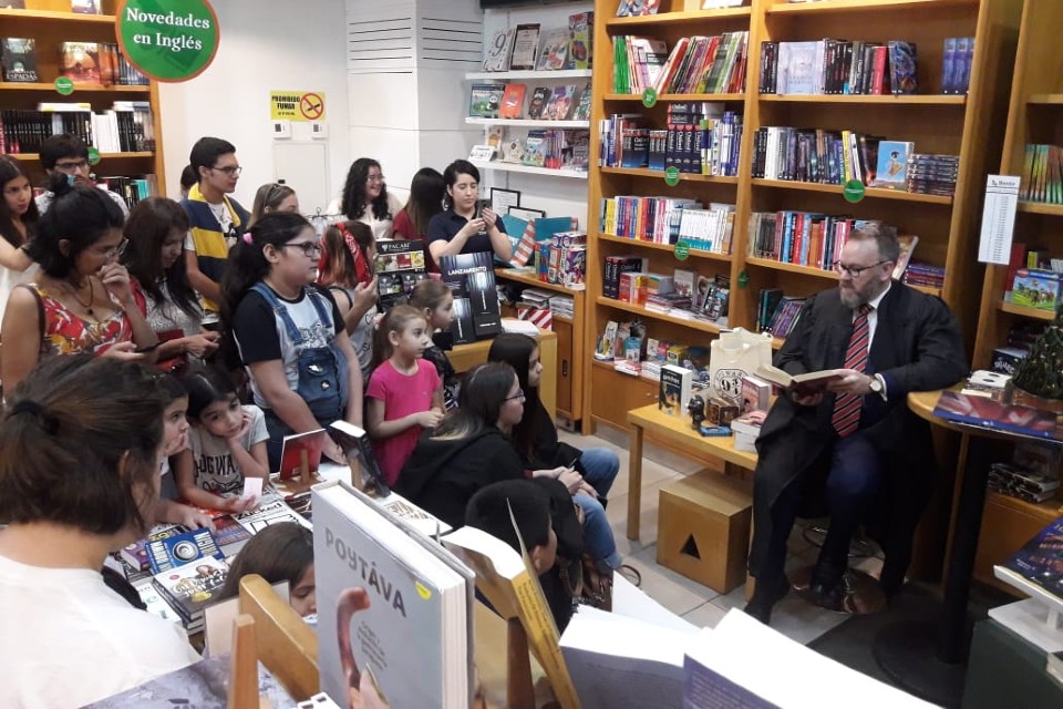 Children surround a person reading a book