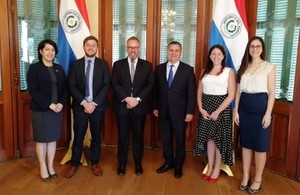 A group of six people standing look and smile at the camera in a formal setting