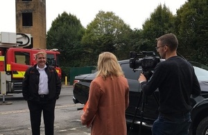 Man being interviewed in front of a fire engine