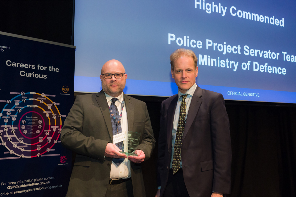 Picture of Police Sergeant Guy Hibbert (to the left), MDP Project Servator Lead Trainer and National Project Servator Trainer collecting the award from Dominic Fortescue (to the right), Government Chief Security Officer. 