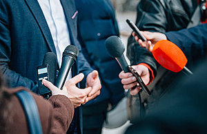 Group of people holding microphones to a person talking