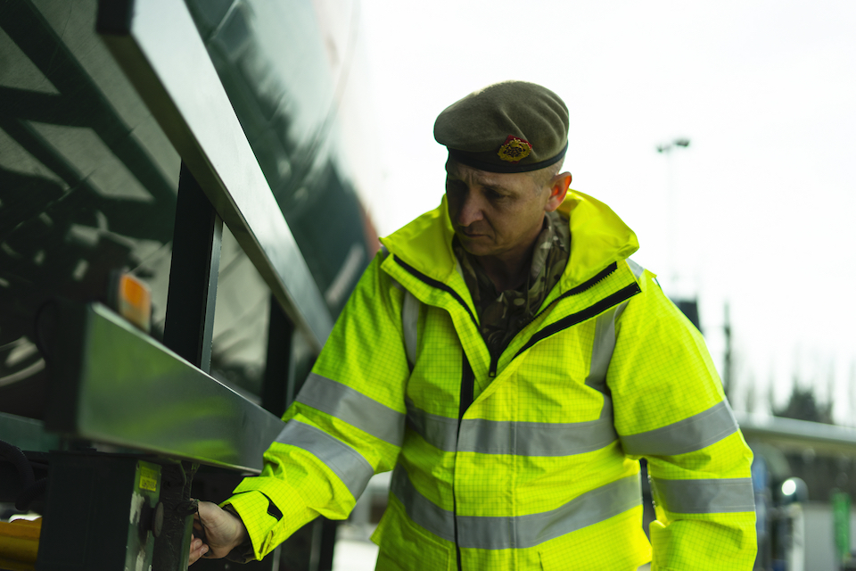 A uniformed member of military personnel works on an oxygen tanker