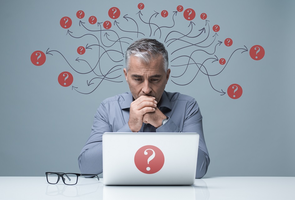 Pensive man at laptop with question marks
