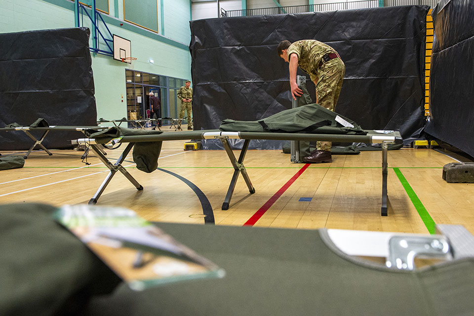 Military personnel helping to install medical equipment in a gym hall