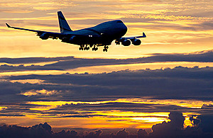 Image of a plane flying at sunset.