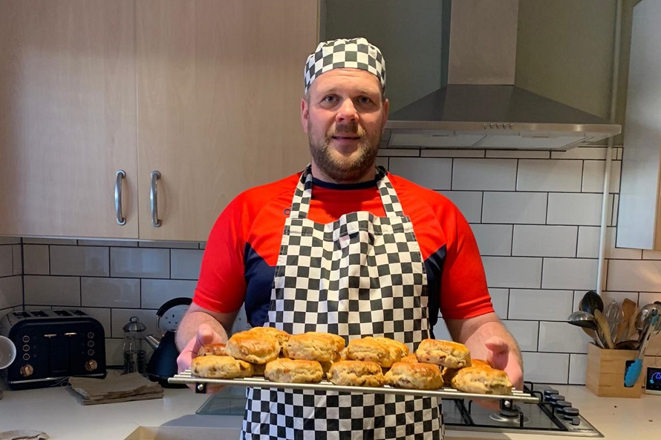 A volunteer baker with a tray full of scones
