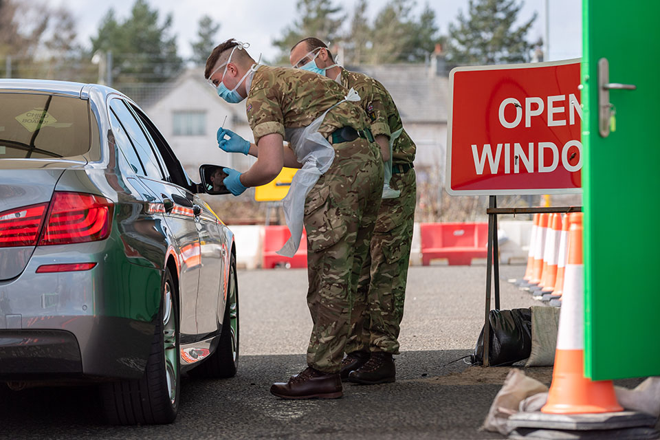 Two soldiers stand at the window of a car, ready to test its driver